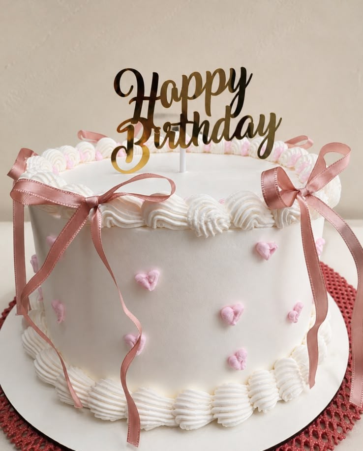 Bolo branco decorado com fitas rosa e topo dourado 'Happy Birthday'